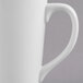 A close-up of a Libbey Ultra Bright White Porcelain Tall Bistro Mug with a handle.