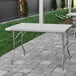 A Regency stainless steel folding work table on a patio.