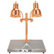 A Hanson Heat Lamps bright copper carving station with two lamps above a metal surface.