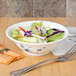 A Blue Bamboo melamine bowl filled with salad on a table with a fork.