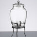 A clear glass jar with a spout on a metal stand.