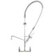 A T&S stainless steel wall mounted pre-rinse faucet with lever handles and a hose.