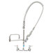 A silver T&S wall mounted pre-rinse faucet with a curved hose.