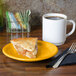 A slice of pie on a Fiesta® Daffodil yellow plate next to a cup of coffee.