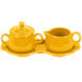 A yellow ceramic tray with a sugar and creamer set on it.