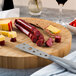 An American Metalcraft bamboo cutting board with sliced sausages and cheese on it.