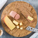 An American Metalcraft bamboo cutting board with cheese, crackers, and meat.