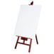 A wooden easel with a white canvas on it.