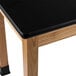 A black science lab table with a laminate surface and wooden legs.