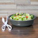 A Fiesta china bowl filled with salad on a table next to a pair of scissors.