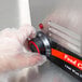 A person's gloved hand turning on a black and red knob on an Avantco countertop food warmer.