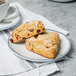 A 10 Strawberry Street Arctic Blue rectangular porcelain plate with two scones on it on a counter with a cup of coffee.