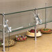 A glass counter top with a Advance Tabco food shield over plates of food.
