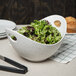 A blue speckled porcelain bowl with cut-out handles filled with green and red lettuce