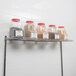 A Regency chrome wire shelf holding jars of spices and a container of brown grains.