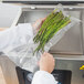 A person using a VacPak-It chamber vacuum packaging machine to seal a bag of asparagus.