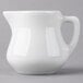 A Tuxton white china creamer pourer with a handle on a white surface.