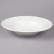 A Tuxton TuxTrendz white china bowl with a scalloped edge on a gray background.