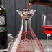 A Franmara silver plated splay wine decanter with red liquid being poured into it.