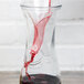 A glass decanter with red wine being poured into it using a glass decanter funnel.