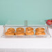 A Cambro clear dome display cover with bagels on a table.