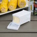 A white rectangular butter container with a white lid and a Fox Run Corn Butter Spreader inside.