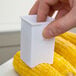 A person using a Fox Run corn butter spreader to spread butter on a corn cob.
