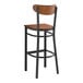 A Lancaster Table & Seating black metal bar stool with a wooden seat and backrest.