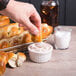 A person dipping a Dutch Country Foods soft pretzel braid into a bowl of salt.