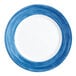 An Arcoroc blue glass dinner plate with a white rim.