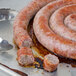 A Fontanini Moda Nostra sweet Italian sausage rope cut into pieces on a pan.