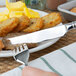 A Oneida stainless steel table knife on a plate of food with hash browns.