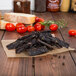 A package of Lancaster County Farms Maple and Pepper Flavor Beef Jerky Strips on a table with bread and tomatoes.