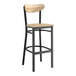 A Lancaster Table & Seating bar stool with a driftwood seat and black frame.
