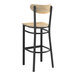 A Lancaster Table & Seating black metal bar stool with a wooden seat and back.