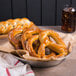 A bowl of Dutch Country Foods soft pretzels with a glass of soda.