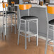 A group of Lancaster Table & Seating bar stools with black vinyl seats and cherry wood backs.