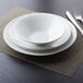 A white bowl and plates stacked on a placemat.