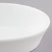 A close-up of a white porcelain oval baker with a rim.
