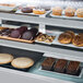 A display case with Avantco shelf tag holders displaying pastries and pastries.