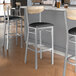 A group of Lancaster Table & Seating bar stools with black vinyl seats and driftwood backs in a restaurant.