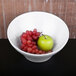 A white Elite Global Solutions Durango melamine bowl with red grapes and a green apple.