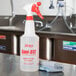 A white labeled bottle of Noble Chemical Sani-512 on a counter with a cloth.