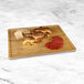 An Elite Global Solutions faux bamboo melamine serving board with meat, cheese, and bread on it.