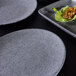 A close up of a Elite Global Solutions Tenaya granite stone melamine plate with food on it.
