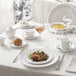 A table set with white Chef & Sommelier bone china plates, glasses, and silverware.