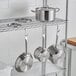 A metal rack with Vigor SS1 Series stainless steel pots and pans on it.