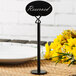 A Tablecraft black metal menu holder with a reserved sign on a table.