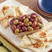 A bowl of Royal Ann Mediterranean Olive Mix with Pits on a table with pita bread.