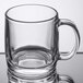An Arcoroc tempered clear glass mug with a handle on a table.